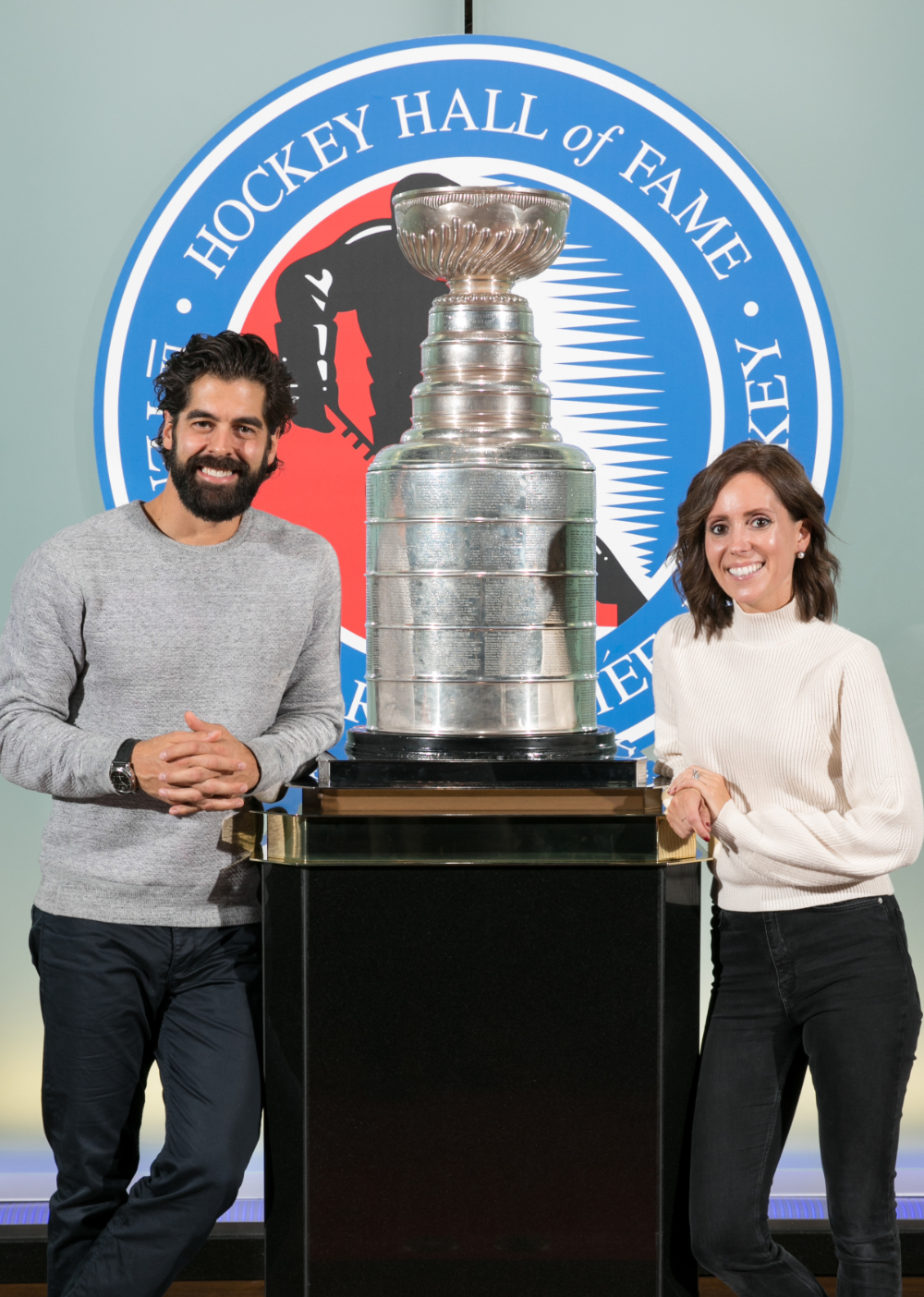 Couple stand on either side of the Stanley Cup in the Great Hall at the Hockey Hall of Fame